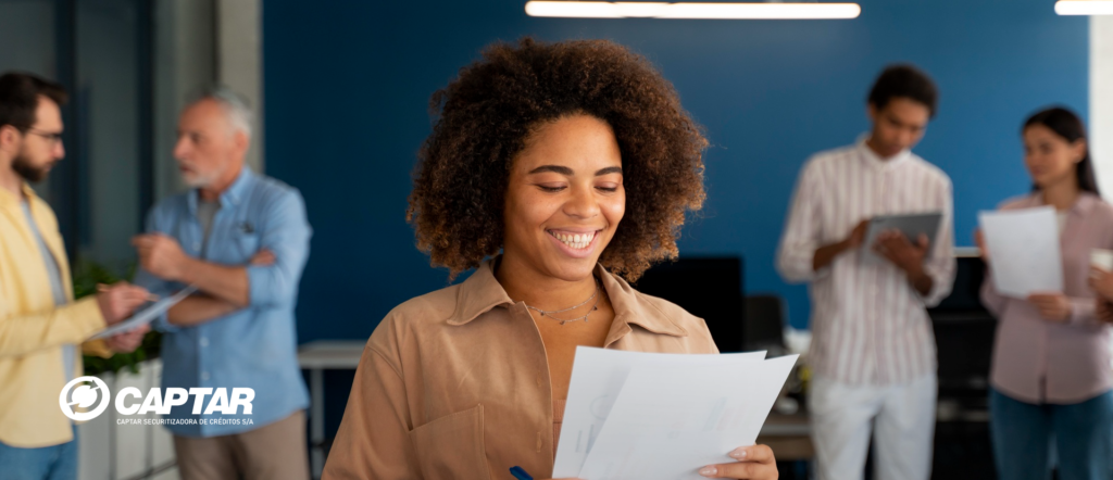 Mulher sorrindo e olhando para uma folha, simbolizando a satisfação e o sucesso com a antecipação de recebíveis para empresas.